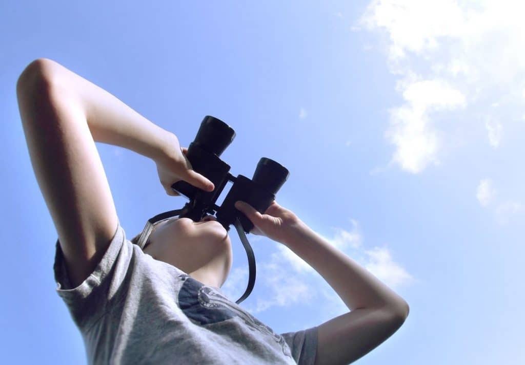 boy-looking-through-binoculars-at-a-passing-airpla-2021-08-29-15-12-49-utc